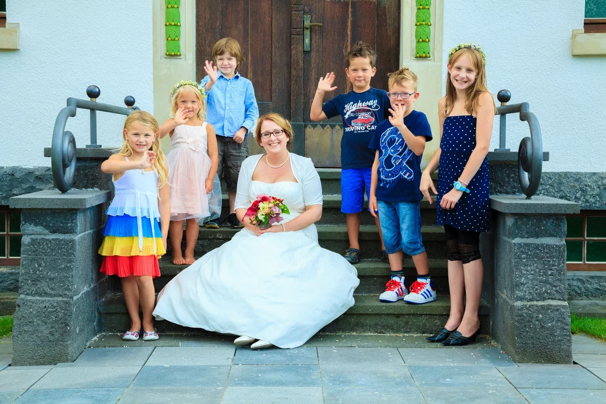 Die Braut mit jungen Gästen auf einer Treppe